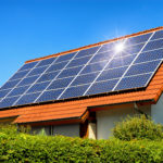 Solaranlage auf einem Hausdach unter dem strahlend blauen Himmel, mit der Reflektion der Sonne